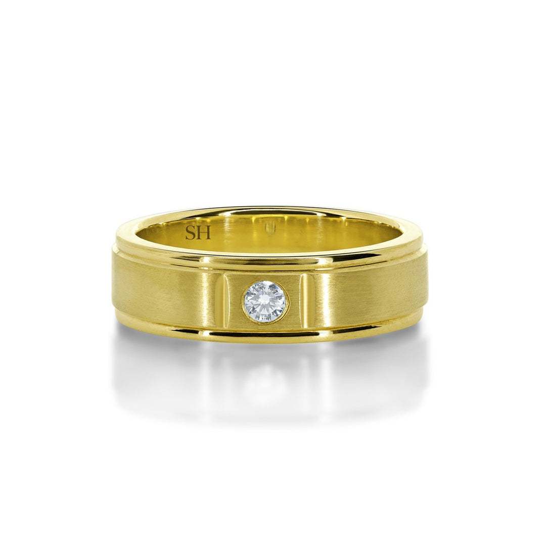 Men's satin finish diamond wedding band with grooves to edges R12-002B-W0074. This classic 18k white gold men's wedding band has been centrally hammer set with a round brilliant cut diamond. The subtlety of the diamond is enhanced with an all over satin finish. The ring has an extra thickness and weight to it and has a uniform width. Although the profile of this ring is flat