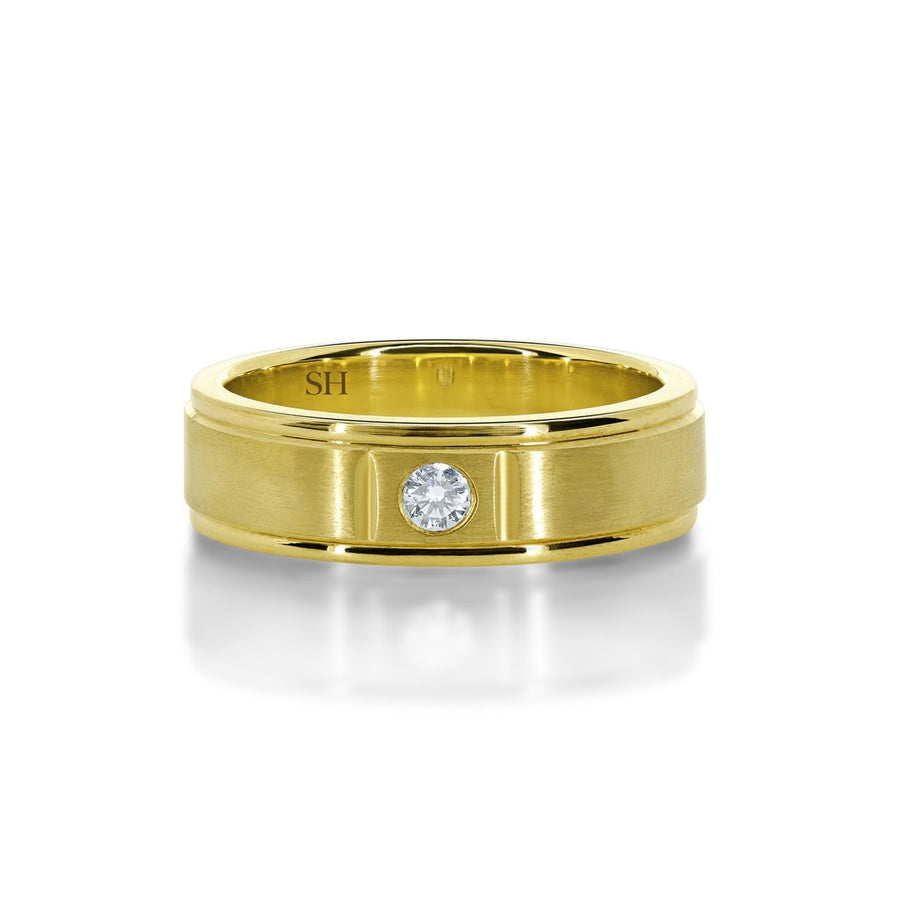 Men's satin finish diamond wedding band with grooves to edges R12-002B-W0074. This classic 18k white gold men's wedding band has been centrally hammer set with a round brilliant cut diamond. The subtlety of the diamond is enhanced with an all over satin finish. The ring has an extra thickness and weight to it and has a uniform width. Although the profile of this ring is flat